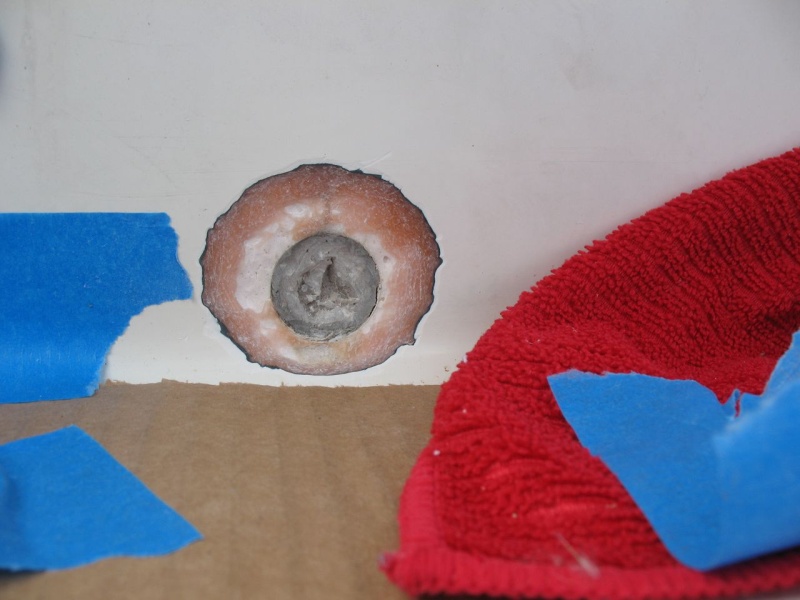A perfectly circular crack in the the center (athwartships) of the splashwell gelcoat  turned out to be a "phantom" drain that had been drilled for but then simply filled and gelcoated over, presumably at the builder or dealers.  Subsequent conversation supplied me with the info that the center location was typically used for twins (my boat has two engines, but not twins).  This type of "repair" (just filler and gelcoat) is destined to crack, which it had.  I ground it back in a taper to prepare for adding fiberglass cloth.  Actually here I had taken away too much of the fiberglass (pink bits) and so ultimately I increased the diameter and improved the taper (leaving more glass to bond to), but I don't have a photo of that.  This gives the idea, anyway.
