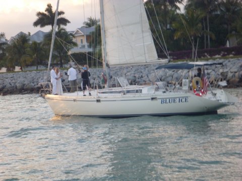 A sunset marriage on the front of a sailboat. He should jump now while he still has a chance