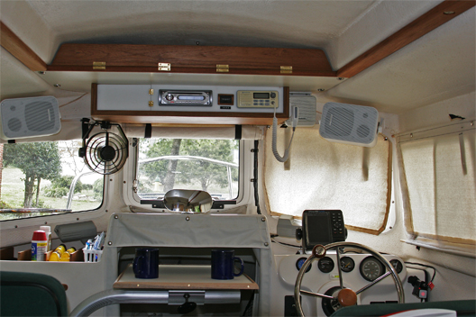 Added overhead console with AM/FM/CD/Aux,speakers' VHF, rode counter and storage door. Upper shelf provides needed storage with quick access behind teak panel. Swivel table can be moved in 3 axes to form dining table, chart/laptop surface, galley table or it can be placed in vertical position to stow