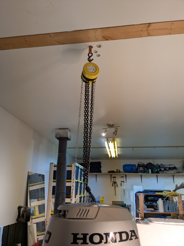 Chain hoist to lift main outboard. 1000lb strap, secured to 3 laminated 2x4s spanning 4 ceiling joists, and to an adjacent 6x6 strutting beam.