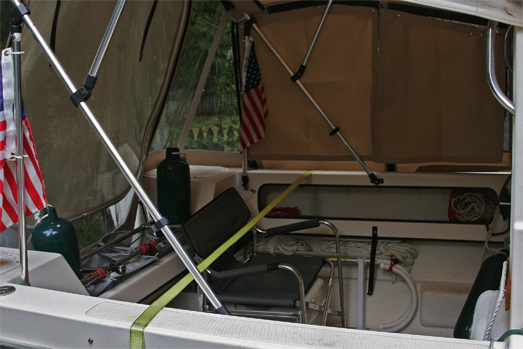 Cockpit with camperback starboard panel removed. Transom bars are most useful mod yet; holds cooler, net boxes for propane / water jugs, fenders, rod holders, etc. Chair just fits over potti to optimize space. Shower enclosure and sunshower makes a handy addition to cockpit.
