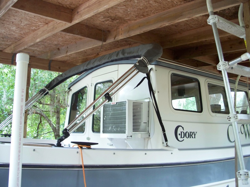 Exterior view of AC. Exterior panel above AC is cut to the same size as the original window and painted white. A cover for the AC will be made in the future. View of the shelter, constructed for a previously owned pontoon boat did not allow enough overhead clearance to consider a roof top AC.