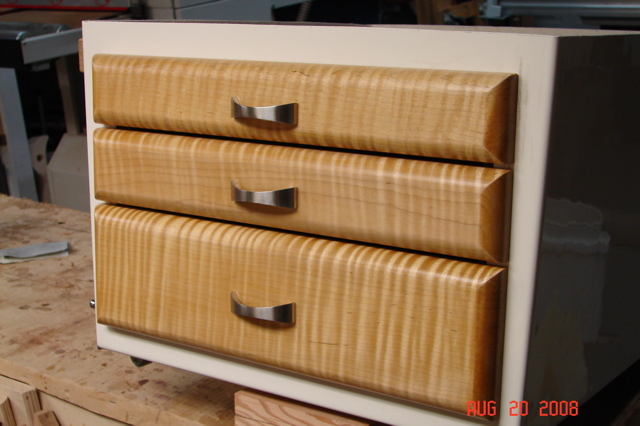 Finished drawer fronts.  Curly maple with 2 coats dark garnet shellac then 2 coats satin poly.  SS pulls from Lee Valley.