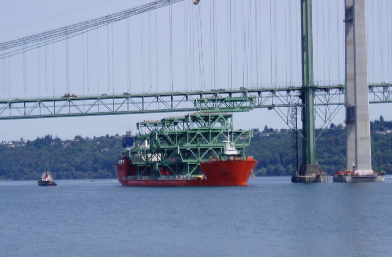 First section being lifted by orange winches on base of tower. Ship will move to the left, and winches will lower road piece onto lifting barge.