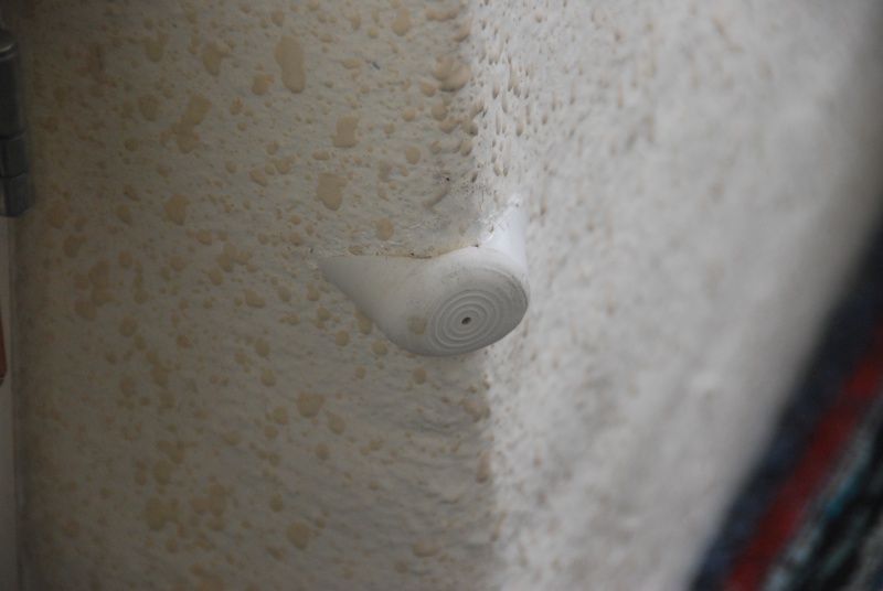 Galley cabinet door bumper made from a pole leg stopper, cut to fit and mounted with 5200