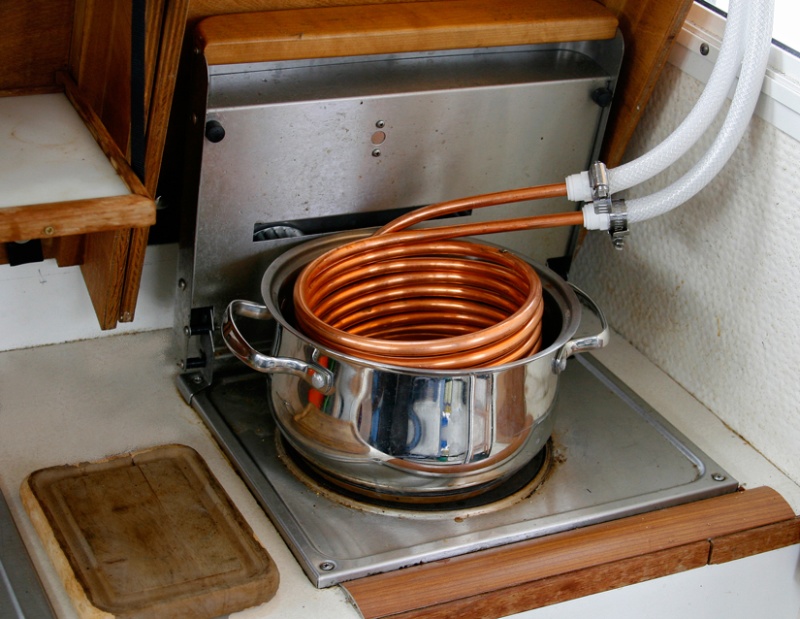 Heat Exchanger is constructed using 25 ft of 3/8 copper tubing coils. The coils are submerged in a pot of water which is heated on the Wallas. THe water hoses are attached to the coil using quick connect fittings. Hoses are stowed out of sight behind the starboard seat cushion for quick deployment.