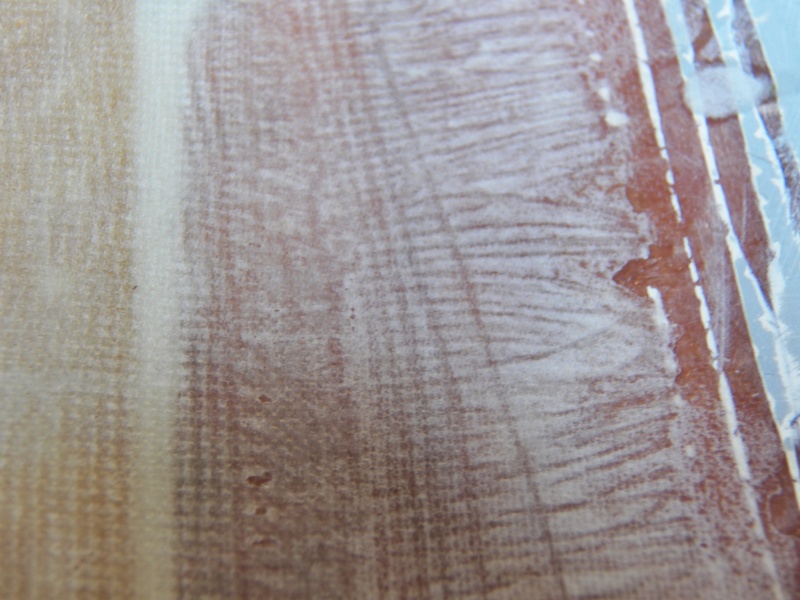 Here is a close up of the edge.  I removed some of the warp (or weft) from the edges to make the layers lie down and fair in better.  The horizontal light line under the fiberglass is lightly colored epoxy putty at the edge of the repair.  The difference in colors made it easy to see where to place the fabric layers.