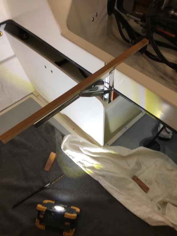 Installing the table hinges. Part of the table rests on the crossmember. The stick is just to ensure it's all level before I screw the hinges to the teak hinge mounts.