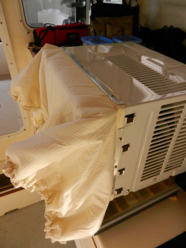 Lisa made the sock to have the exact rectangular opening of the AC unit on one end,, and  the measured outer window frame on the outer edge.  

I used thin aluminum strips and VERY short sheet metal screws to fasten the "sock" to the AC unit.  The outer edge has 1/4" bungee cord in a hem and one of those squeeze cinch thingies.

There is two fabric layers with some insulating foam in between them to help (marginally) prevent air-to-air exchange.