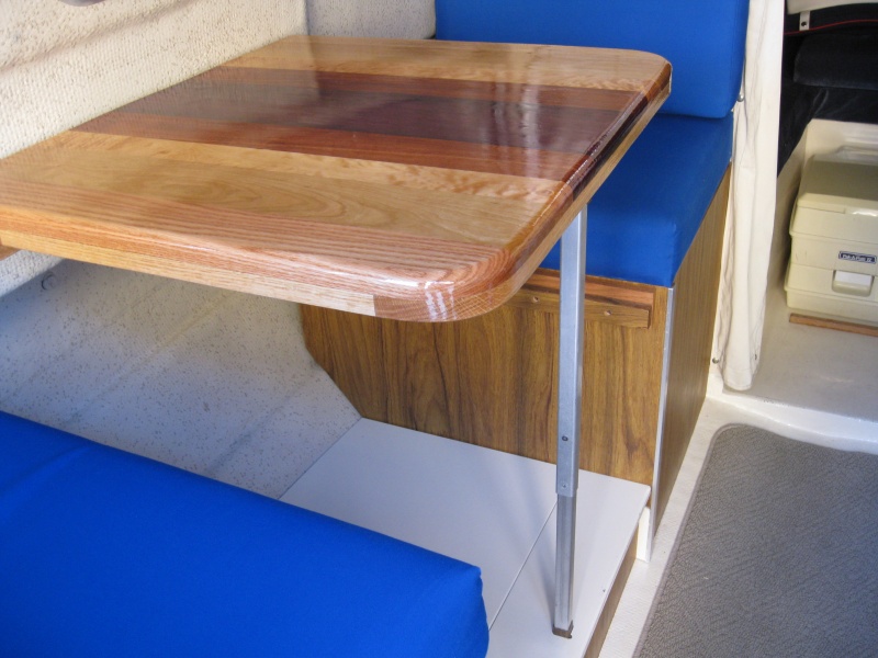 New table top - Purpleheart, Mahogany, Maple, Cherry, Oak.  Solves 3 issues: 1. Couldn't put old table in or out of berth position without moving seat cushion.  New table narrower. 2. Seat and back cushions use same foam thickness, but seats have 3/4" plywood bottom.  In berth position, table was too low.  New table thicker. 3.  Metal edge around old table made picking up playing cards harder.