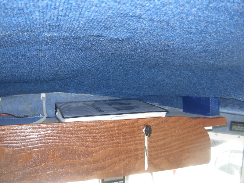Overhead storage above center windshield.  With the original open shelf we were always being "bombed" by stuff falling from the over head bin.  I lowered the shelf by inserting a 2x2 and using longer bolts.  The front cover, or door is a piece of 1/4 ply held in place with wing nuts.  See next photo for the closed position view.  The blue "headliner" lining was our test for the headline fabric.  It worked well, but my application was poor so we had a professional do whole cabin interior with a golden brown headliner fabric.