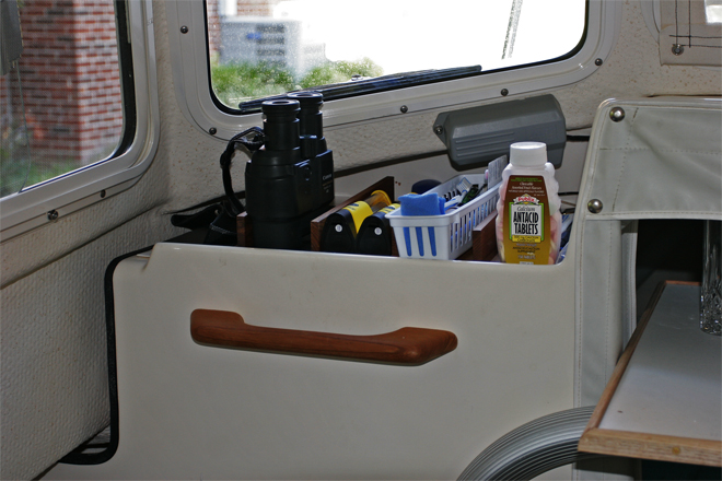 Port console shelf is divided by teak kitchen drawer dividers to keep stuff organized. Grippy mats in each section keep stuff from shifting around. The bride requested a grab handle.
