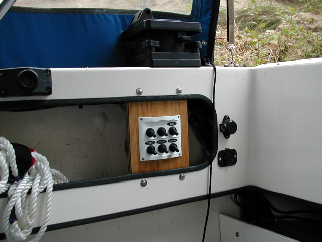 (rogerbum) 6 switch electrical panel in cockpit.  Top L is Man Fore Bilge, Top C is Man Aft Bilge, Top R is Auto Aft Bilge, Bottom L is cockpit lighting (12V rope light to be installed), bottom C is SpotLight, bottom R is new 12V outlet (to right of panel, below downrigger power)