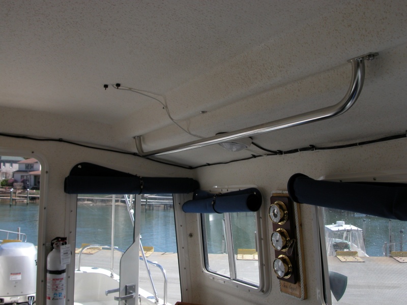 (Sea Angel) Port Side Grab Rail, Fire Extinguisher and WX Station. 

The WX Station is mounted on a hinged base so the clock battery can be changed. Two brass eyes are positioned in the side section with a brass 'pin' made from a toilet support arm, bent and cut to length with short line attached. The 'Sea Angel' name is mounted with a "Clear Mailing Label" designed for a laser printer and covered with acrlyic spray.