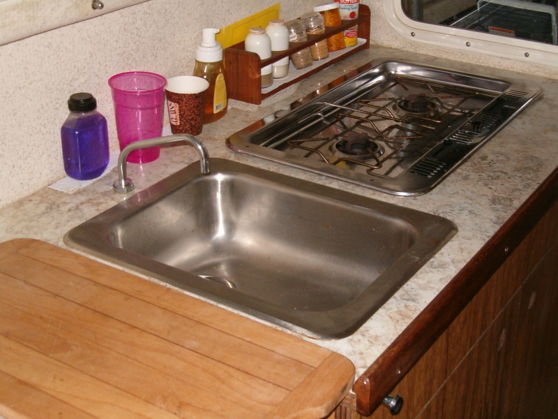 Sink with pressure water system and alcohol stove with cover used as extra counter space.