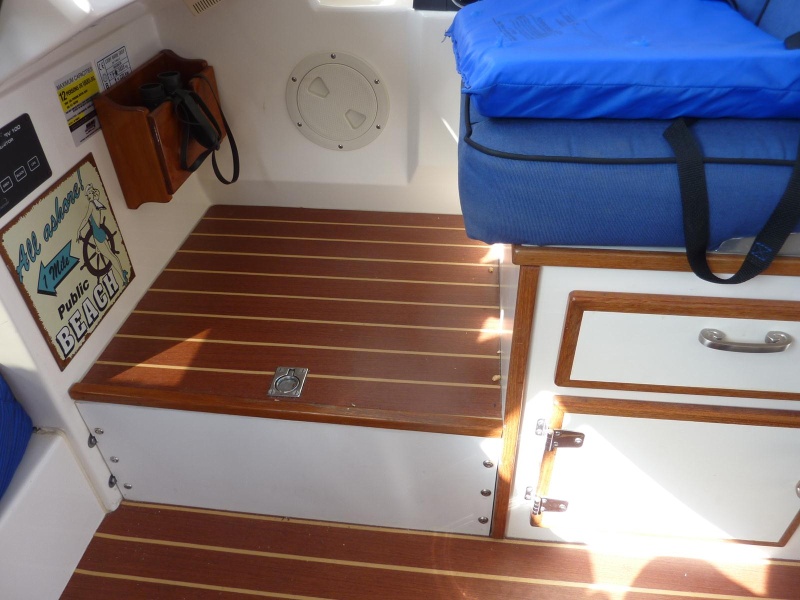 Storage area under the raised deck at the front of the helm seat.  Easy access for navigational items.
