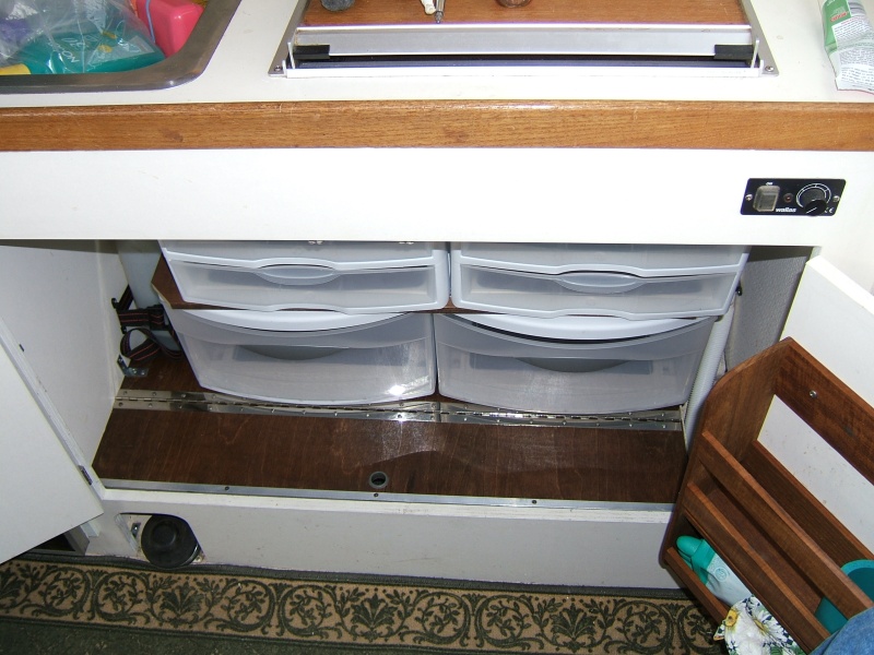 storage for pots and pans below hinged swing up door - pull out plastic drawers for plates, etc.