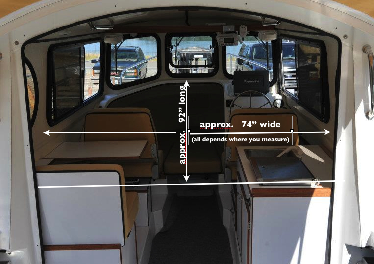 The cabin, shown with the bulkhead removed in Les' photo on Facebook, in our view is quite large.  One could argue that it is really 7' 7" long, and the 5' 9" berth extends out 18" into the cabin, which allows a person to sit on the berth while visiting with three other people in the cabin, as well as allowing easy access to the portable toilet under the center cushion.  Of course, when the left, rear cushions are put into place, the berth extends to a total length of 7', reducing the floor space in the cabin at night.  Visually however, the cabin still looks 7' 7"' long.  That's the genius of this design.  Please notice, too, the width of the floor in front of the dinette and galley:  it is wide enough for two people to easily pass one another, which we feel is an important feature for living comfortably in a small boat.