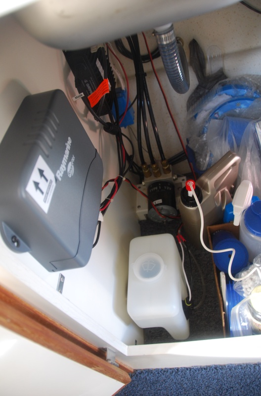 The water tank is located under the sink and below the Autopilot CPU - beside the hydraulic pump.
NOTE: Windshield Washer Fluid should be mixed with fresh water to minimize any 'crud' buildup in the lines and heads with full strength used as you would your car when approaching the colder seasons.

The brown jug, behind the white washer tank, is a pump sprayer from yard work that I used to spray fresh water on the windows. (One more item I can remove in the near future.)