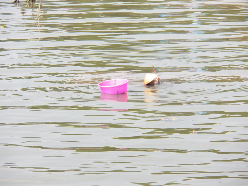 This woman had a "sifter" on the end of a pole and appeared to be harvesting snails from the muddy bottom.