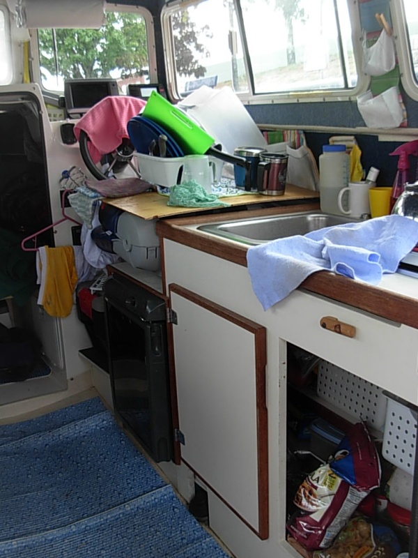 Two Bears in "living mode".  Note that cabnet door is missing and is now a flat work surface on top of helm seat.  Walls and ceiling have been lined with indoor/ outdoor carpet to 1) reduce condensation, and 2) to hold Velcro based pockets and LED lights
We purchased plastic baskets to sit on shelves which helps with organization under the sink.
