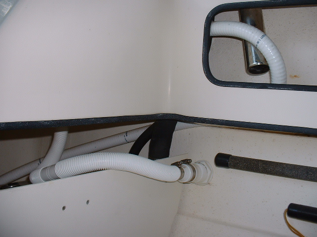 Water from the pump flows through the hose that bends by that rod holder and enters the tank. The other hose is the drain that is continuously discharged overboard.